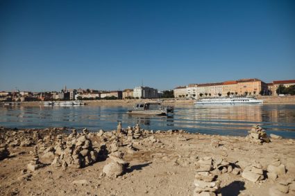 „Putem merge pe jos până în România”: Dunărea, la niveluri istorice minime, descoperă epave și amenință producția de energie din zonă.